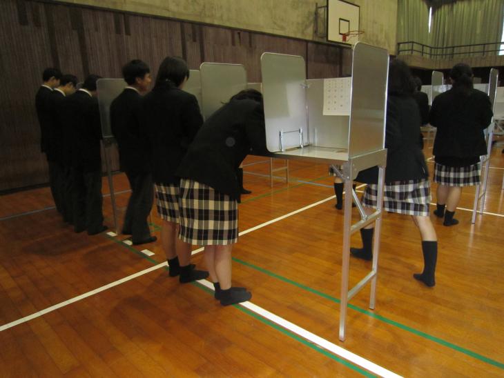 投票用紙に記載をする学生